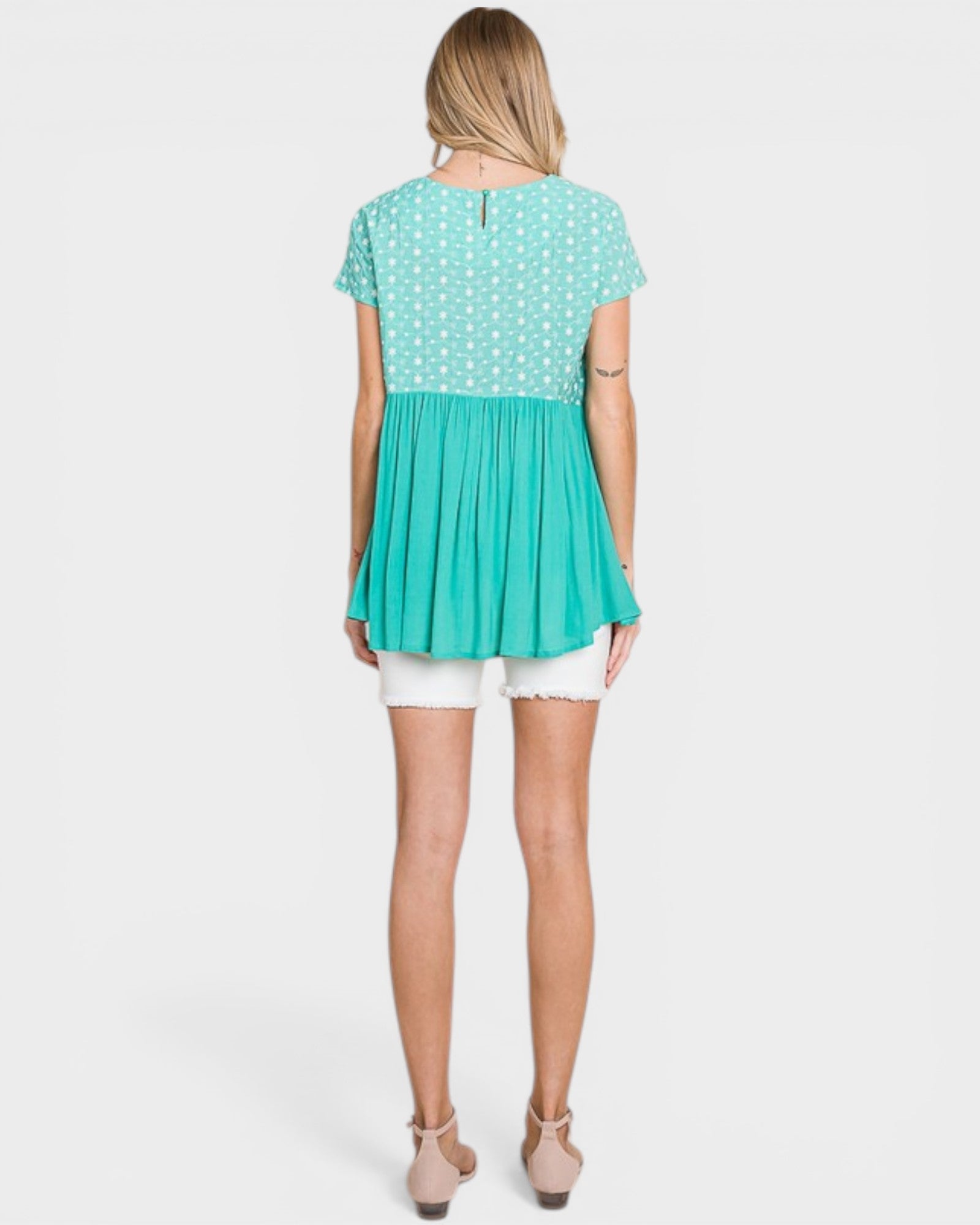 Woman wearing a two-tone dress with a polka dot top and solid skirt on a white background