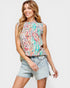 Woman wearing a colorful sleeveless top and denim shorts on a light gray background