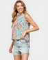 Woman wearing a colorful sleeveless top and denim shorts on a plain background