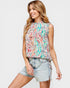Woman wearing a colorful sleeveless top and denim shorts on a white background