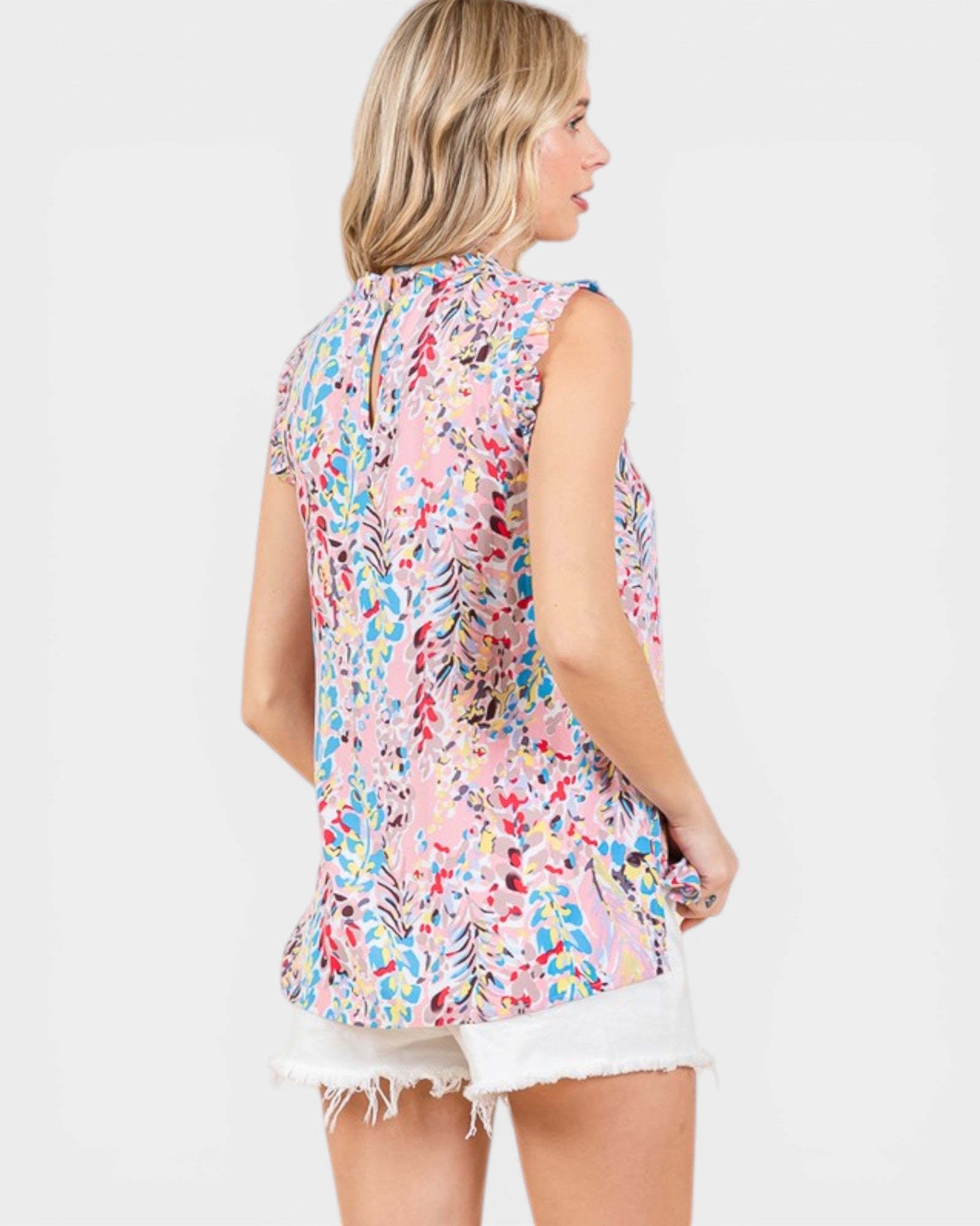 Woman wearing a colorful floral sleeveless top on a white background