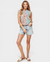Woman wearing a floral sleeveless top and denim shorts on a white background