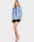 Woman wearing a blue and white patterned top with black shorts on a white background