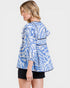 Woman wearing a blue and white patterned top on a plain background