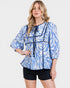 Woman wearing a blue and white patterned blouse with black trim on a white background