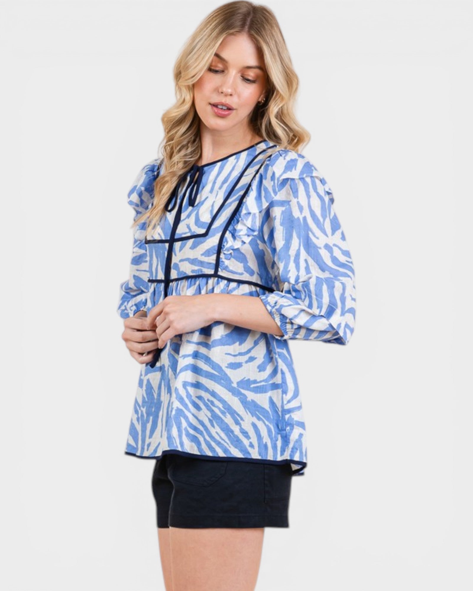Woman wearing a blue and white patterned top on a white background