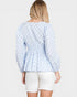 Woman wearing a light blue polka dot blouse and white shorts on a white background