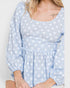 Light blue polka dot blouse worn by a person on a white background