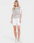 Woman wearing a leopard print top and white shorts on a white background