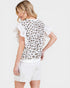 Woman wearing a white blouse with leopard print back and ruffled sleeves on a light background