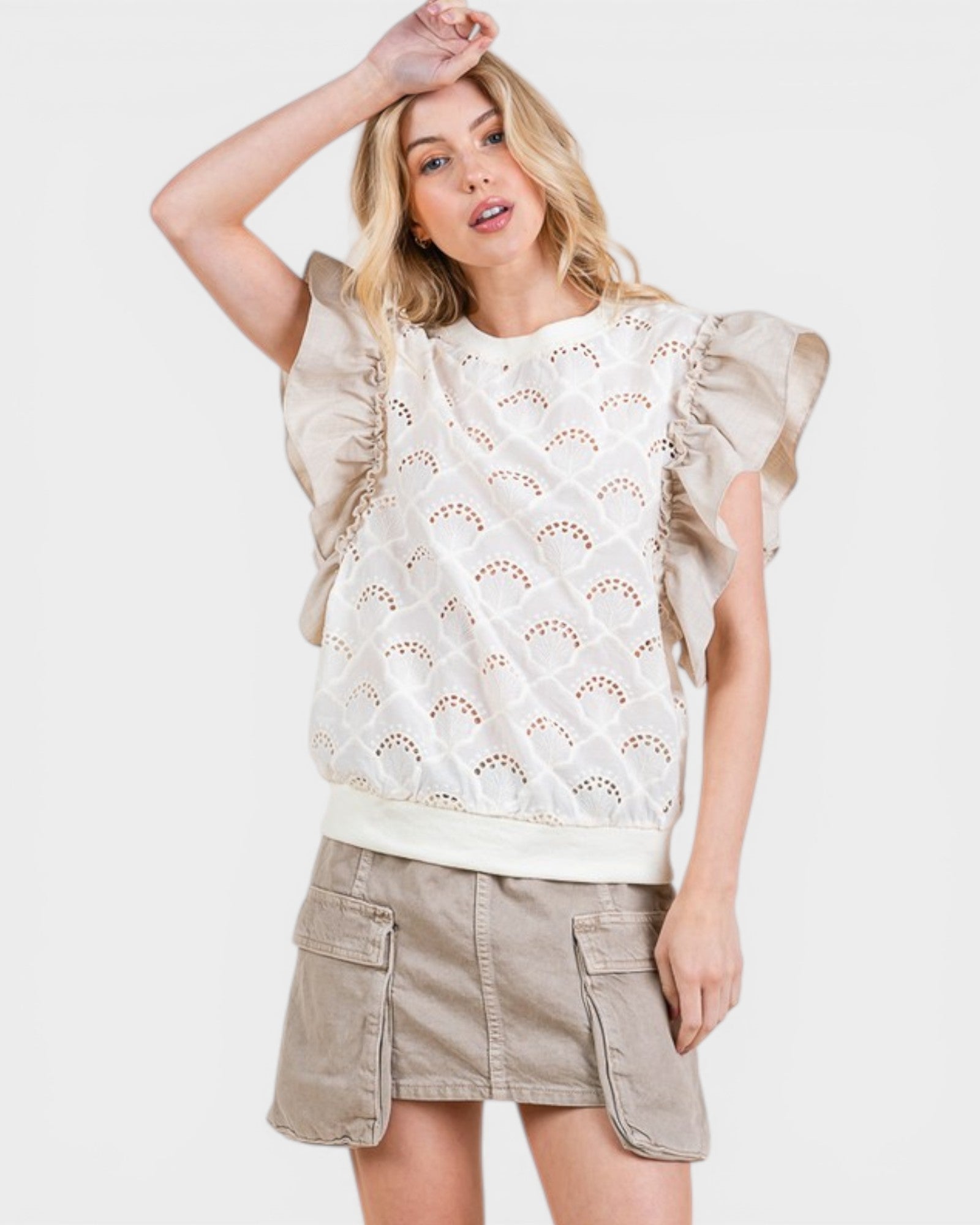 Woman wearing a beige lace top and shorts on a white background
