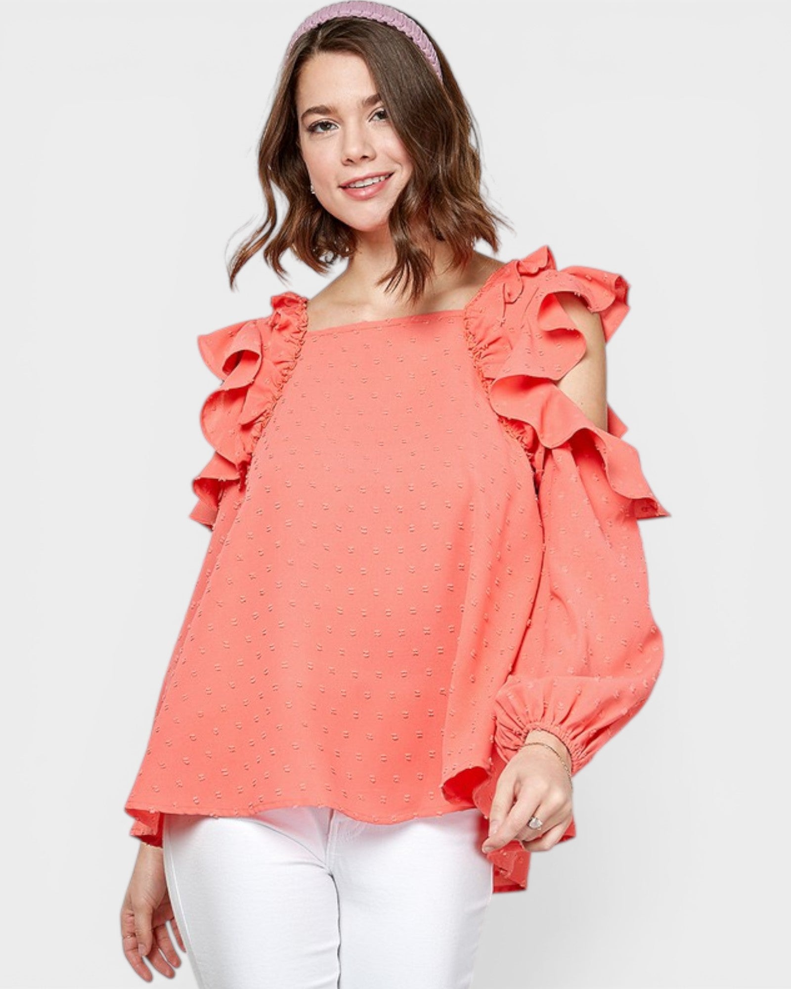 Woman wearing a coral blouse with ruffled sleeves on a white background