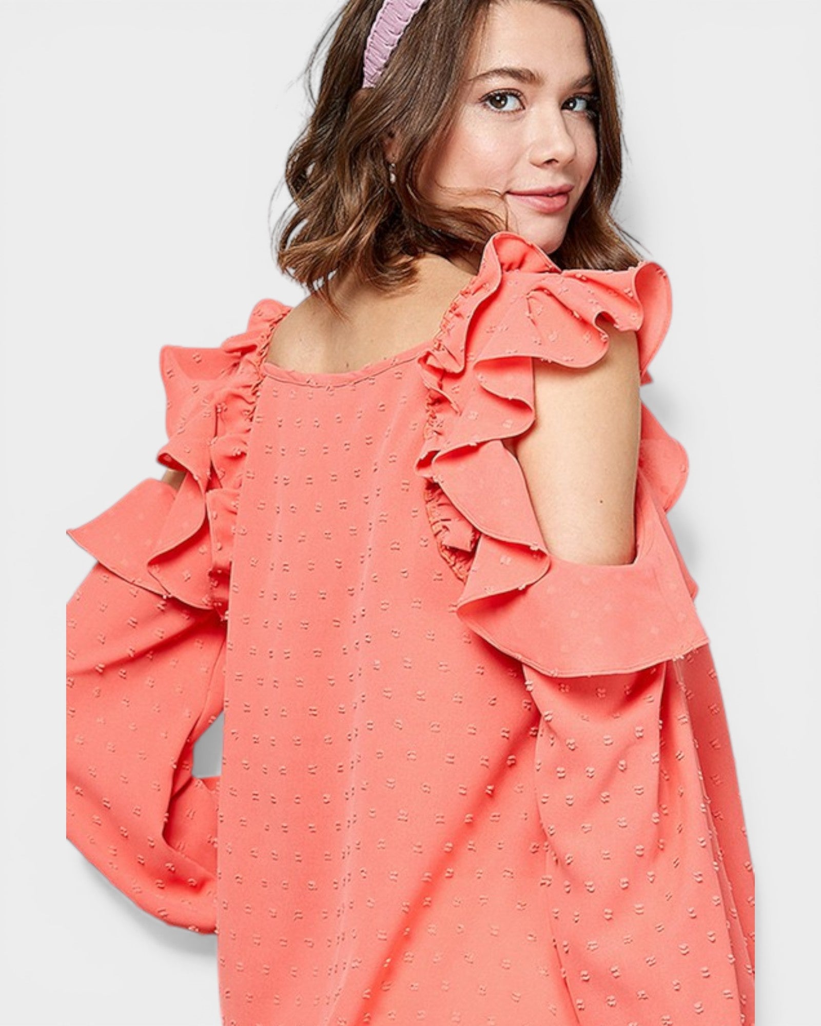 Girl wearing a coral dress with ruffled sleeves on a white background