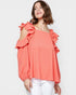Woman wearing a coral off-shoulder top with ruffles on a white background