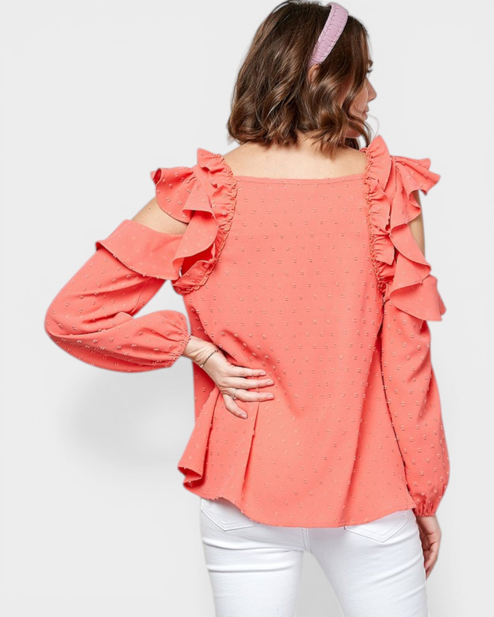 Woman wearing a coral blouse with ruffled sleeves on a white background