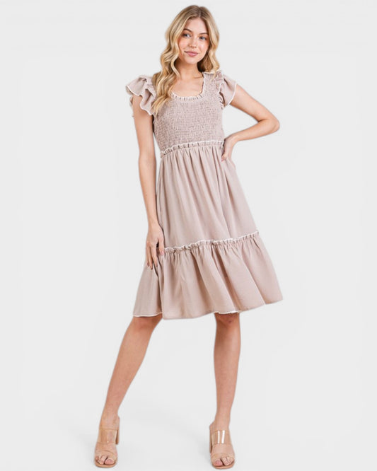 Woman wearing a beige dress with lace details on a white background