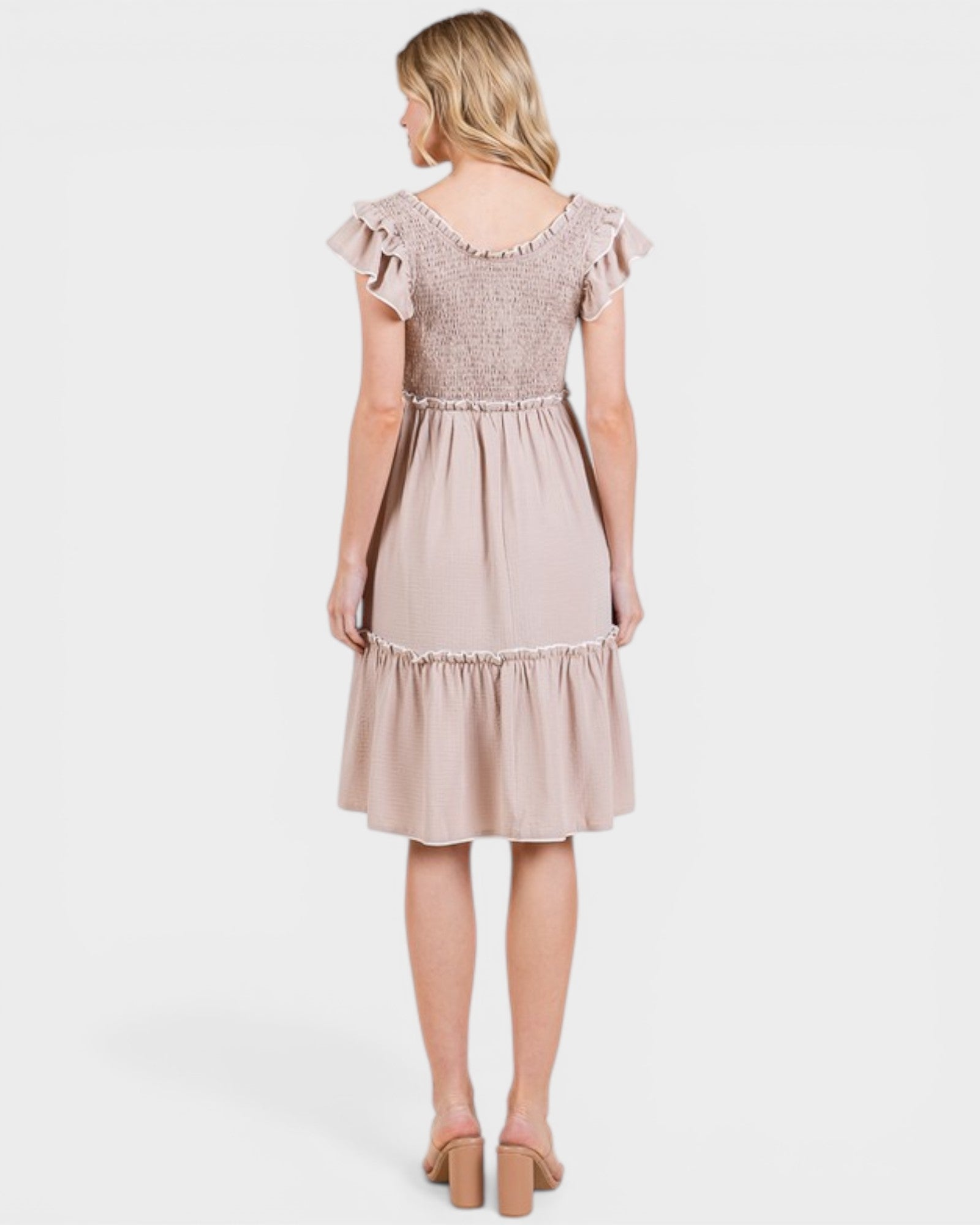 Woman wearing a beige dress with lace details on a white background