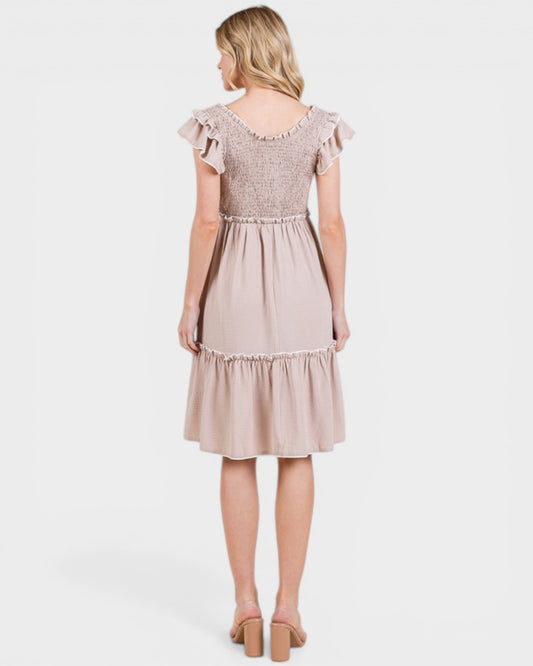 Woman wearing a beige dress with lace details on a white background
