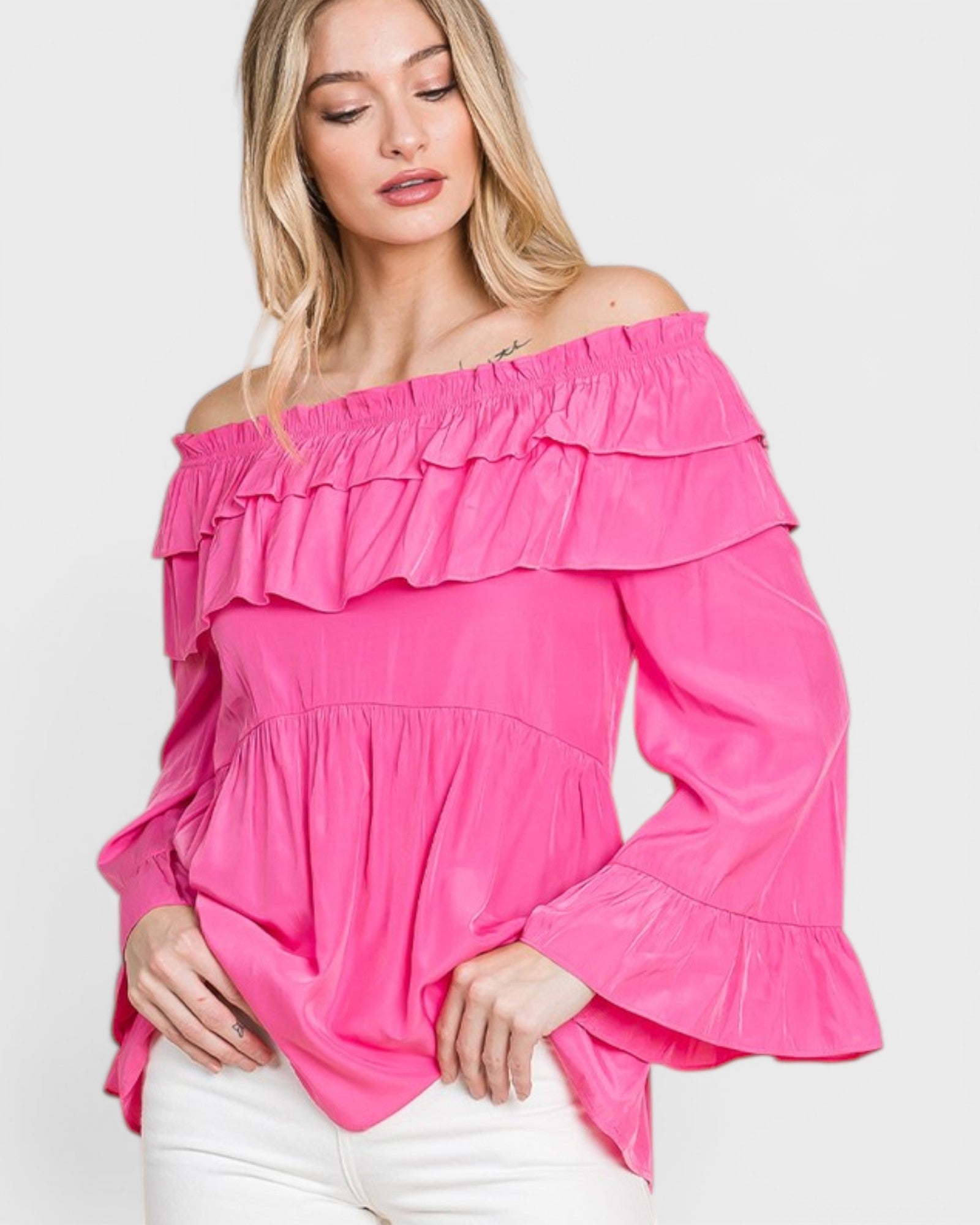 Woman wearing a bright pink off-shoulder ruffled top on a white background