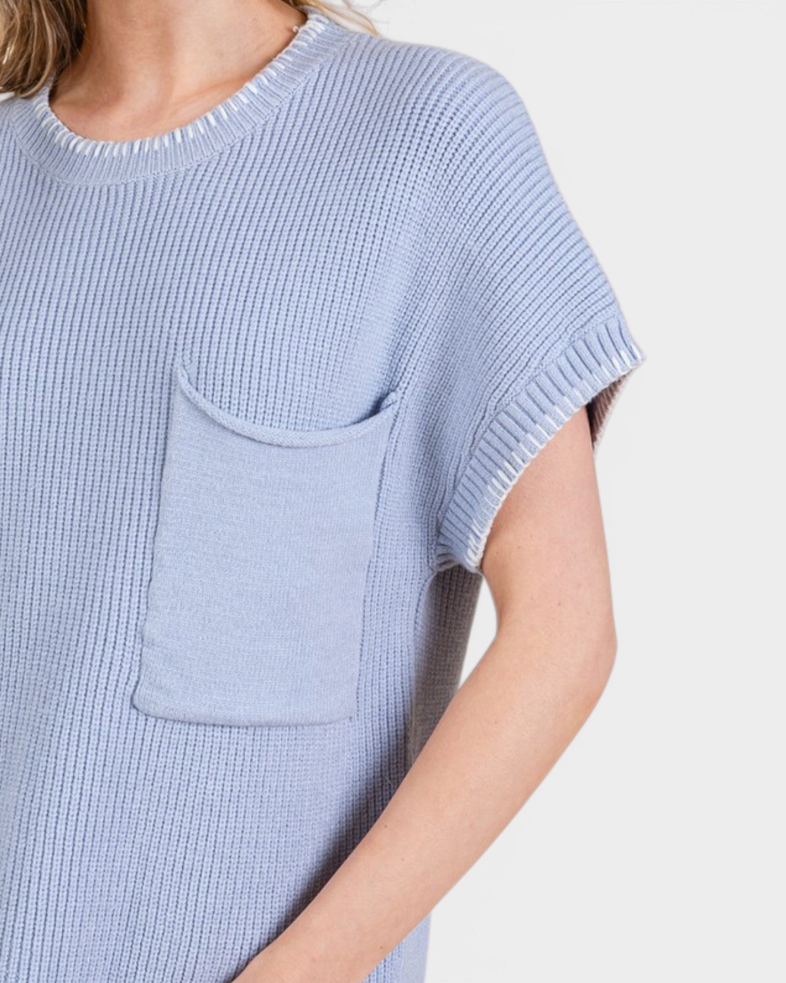 Light blue knitted top with a pocket on a white background