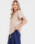 Woman wearing a beige knit top with a pocket on a white background