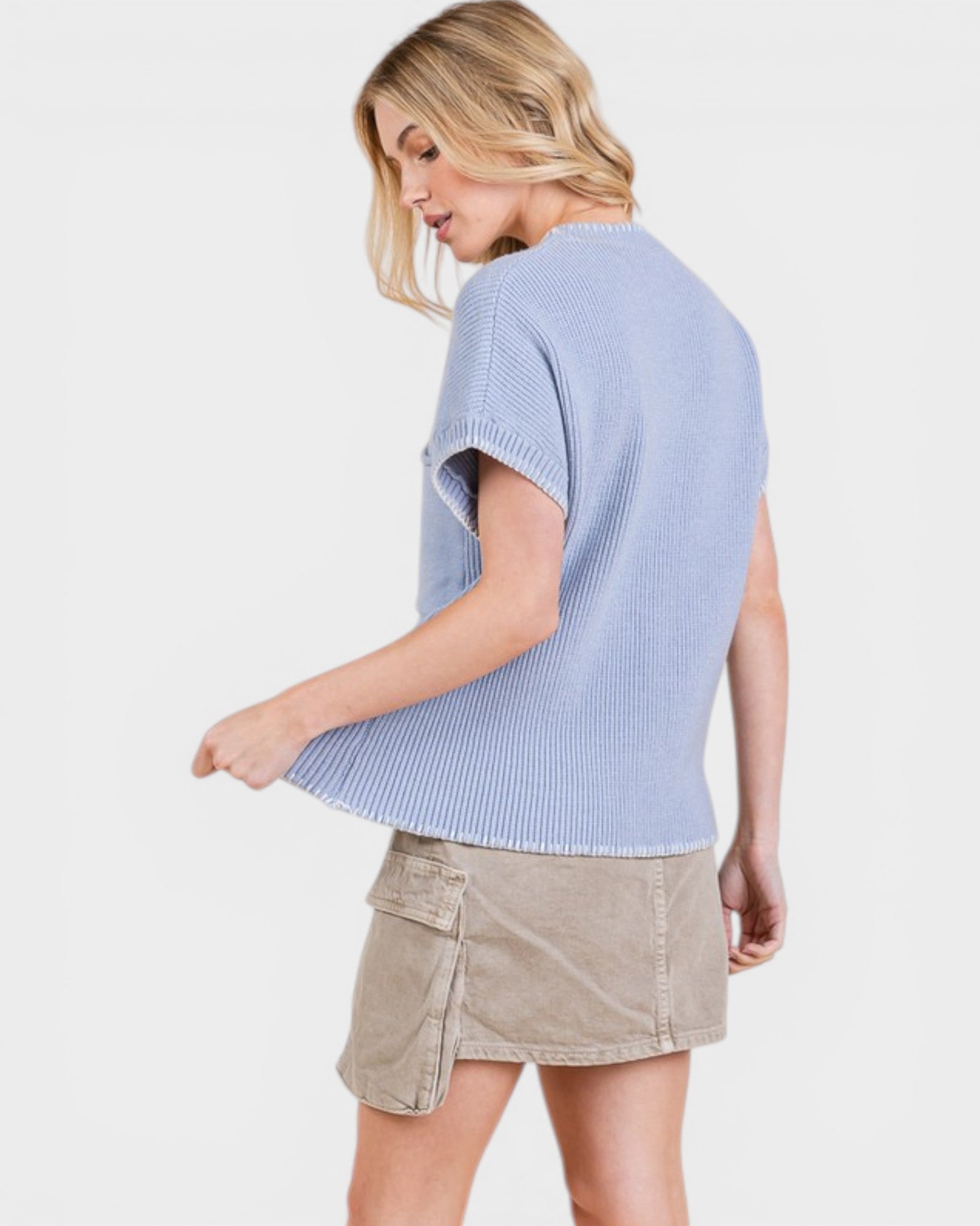 Woman wearing a light blue sweater and beige skirt on a white background