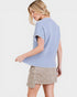 Woman wearing a light blue sweater and beige skirt on a white background