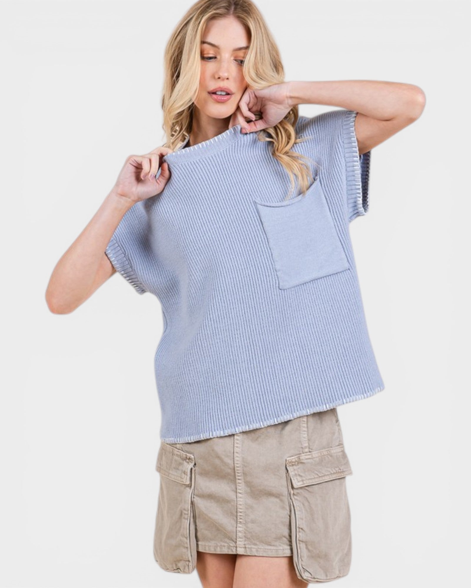 Woman wearing a light blue sleeveless knit top with a pocket on a white background