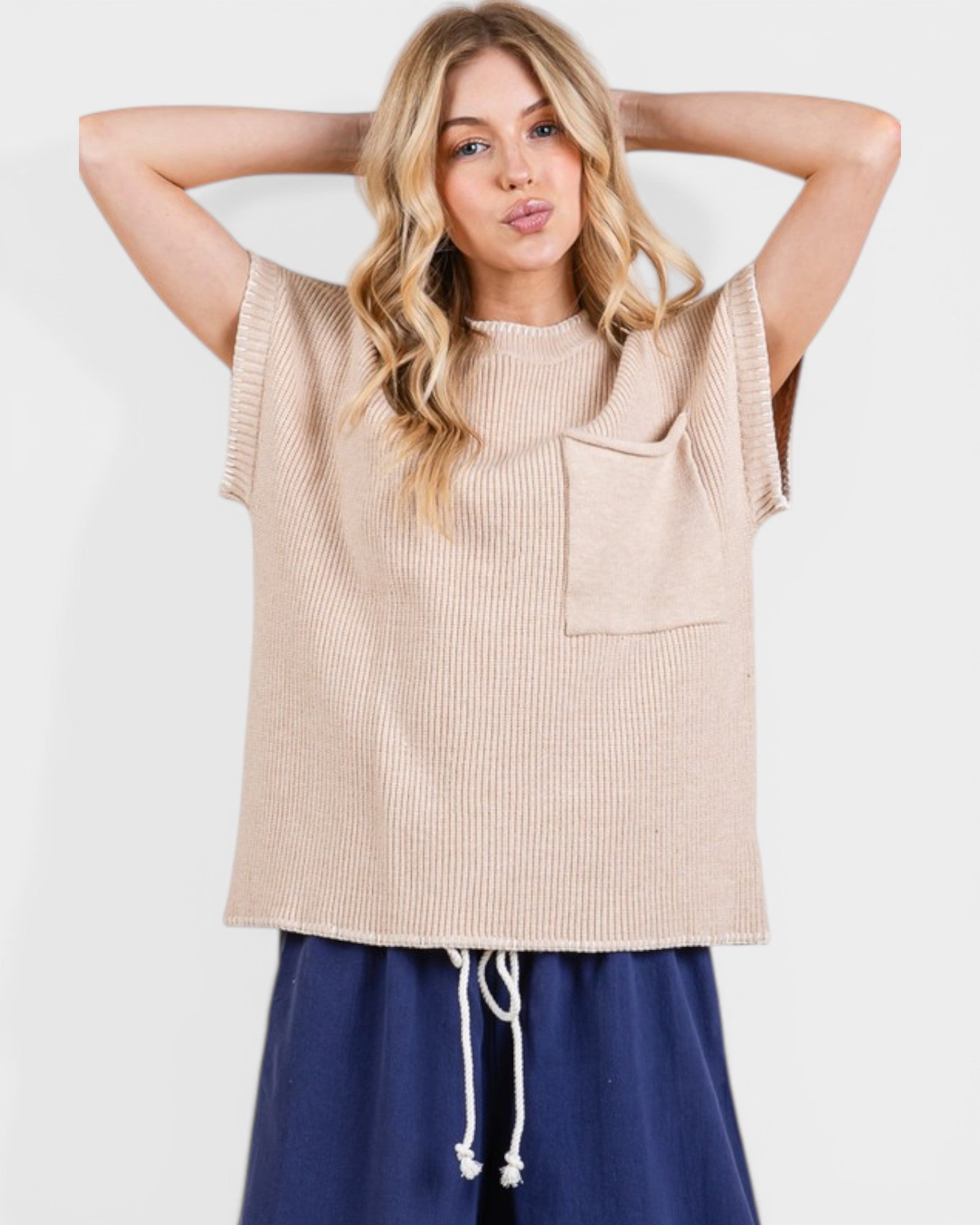 Woman wearing a beige sleeveless top with a pocket on a white background