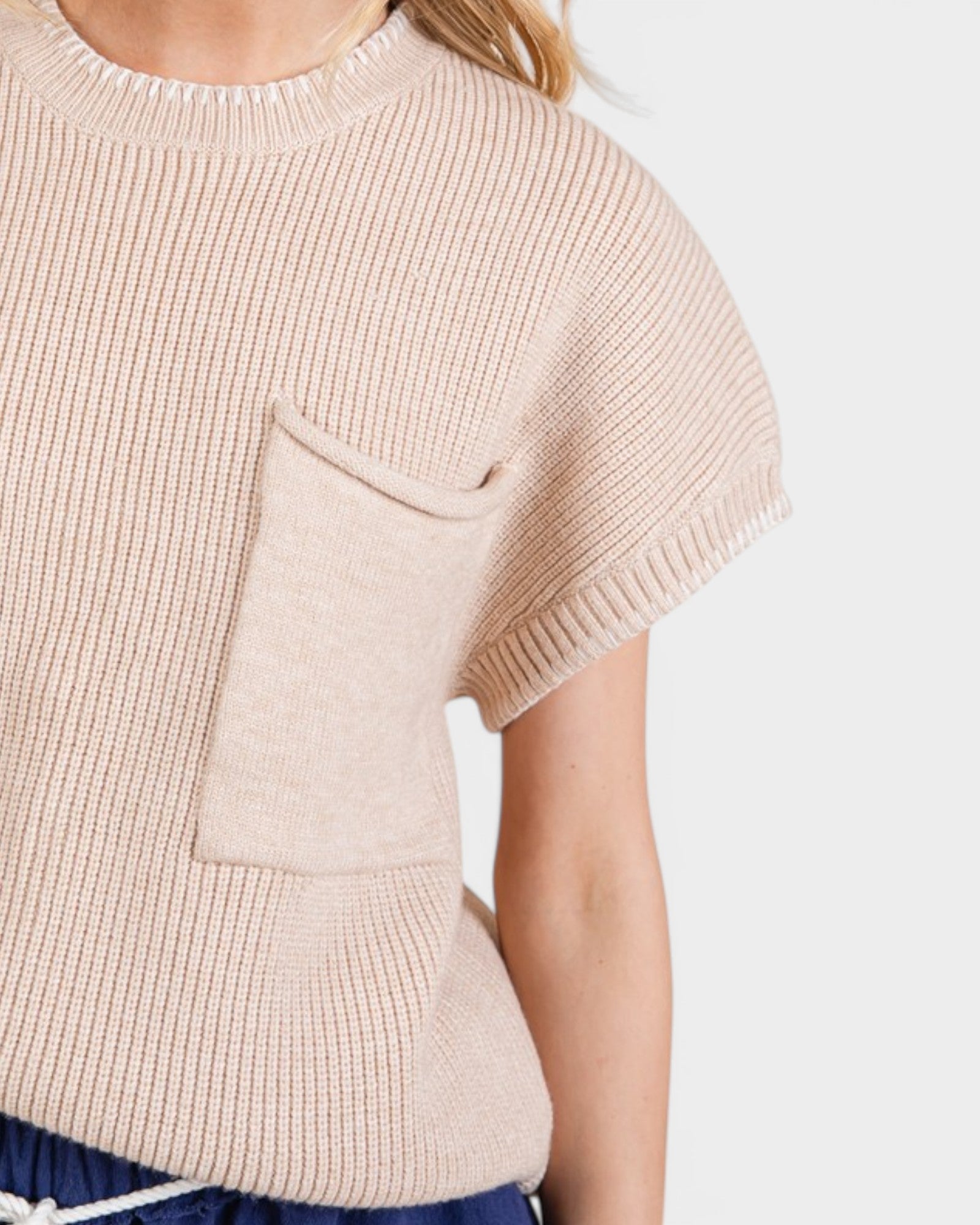 Beige knitted poncho worn by a person on a white background