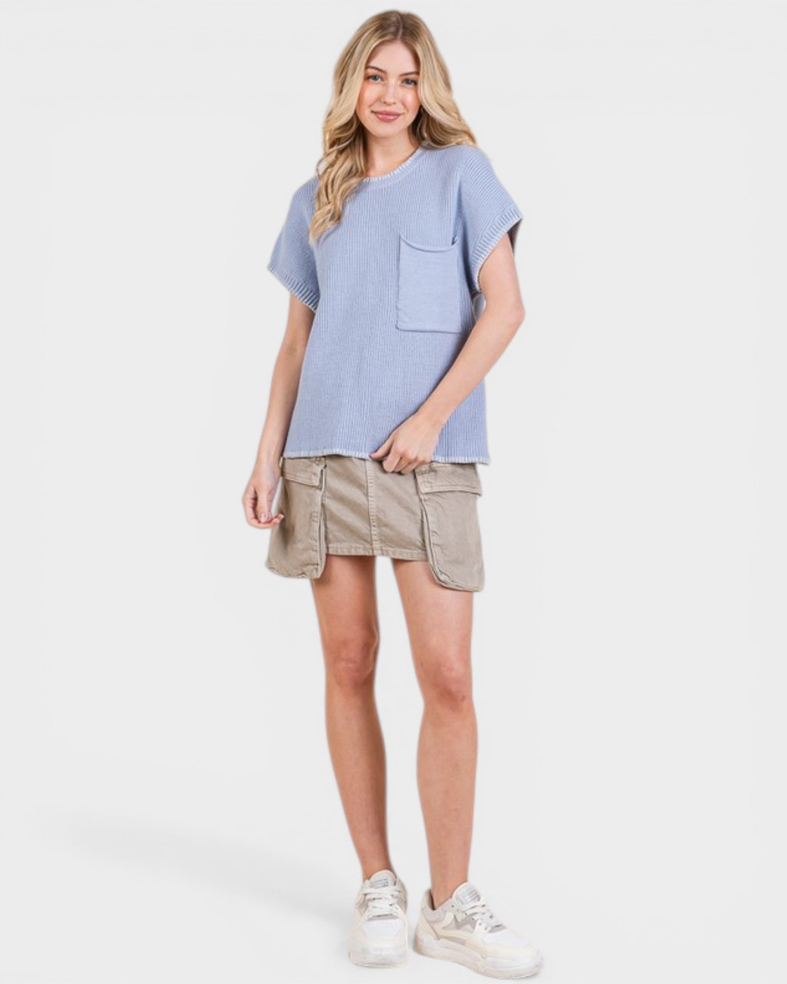 Woman wearing a light blue top and beige skirt on a white background