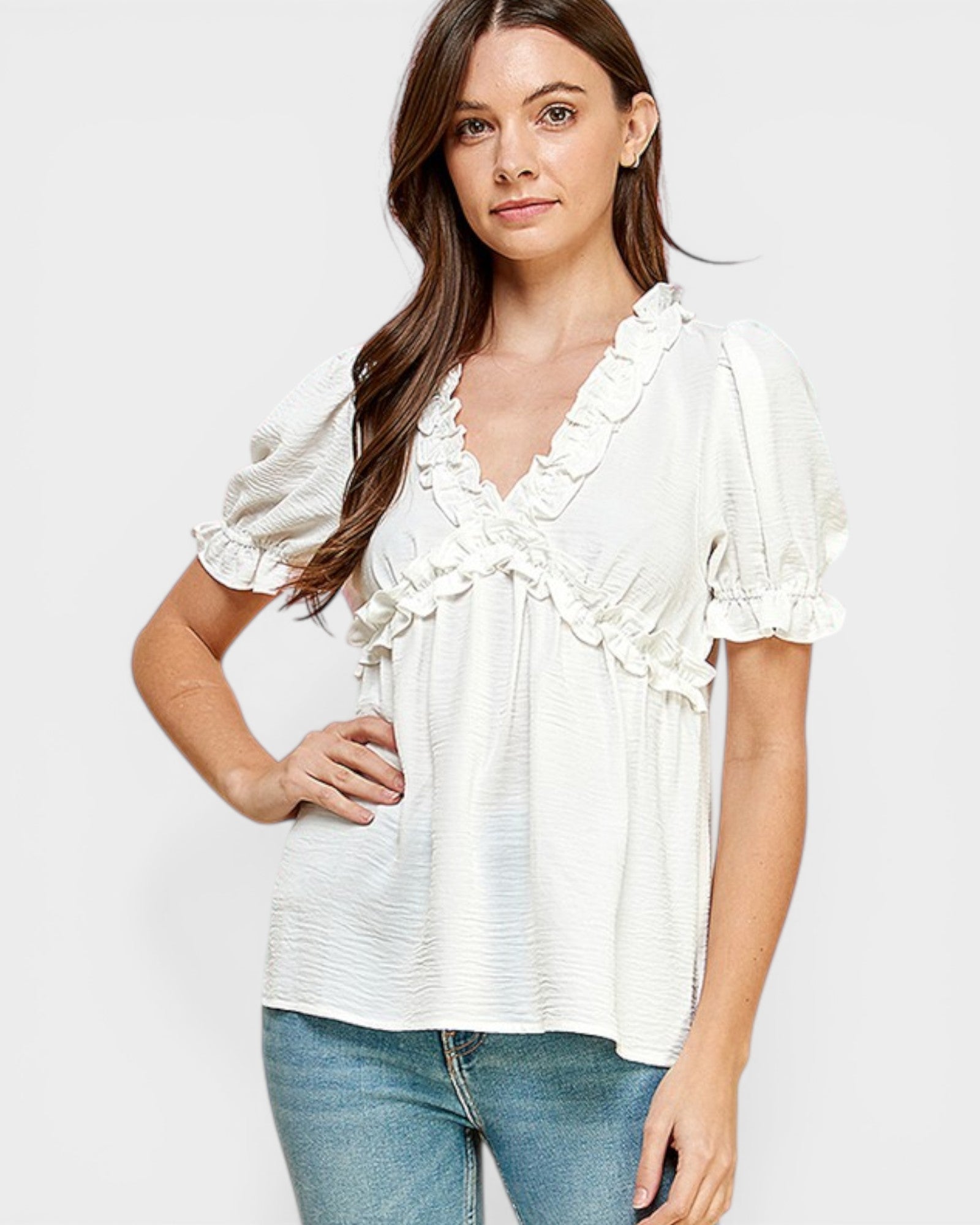 Woman wearing a white blouse with ruffled details on a plain background