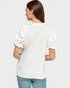 Woman wearing a white blouse with ruffled sleeves on a plain background