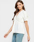 Woman wearing a white blouse with ruffle details on a plain background