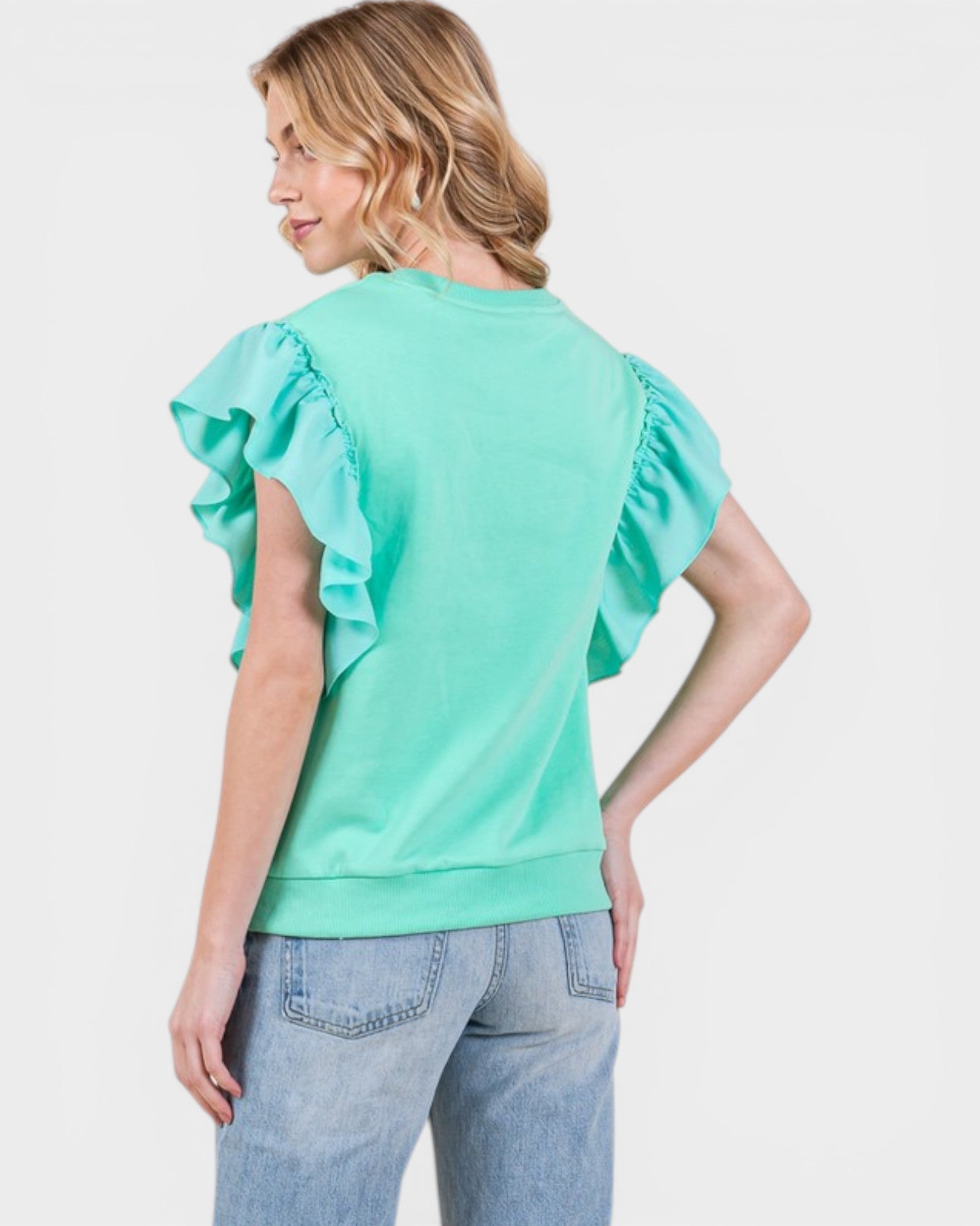 Woman wearing a light green blouse with ruffled sleeves on a white background