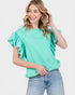 Woman wearing a mint green top with ruffled sleeves against a white background