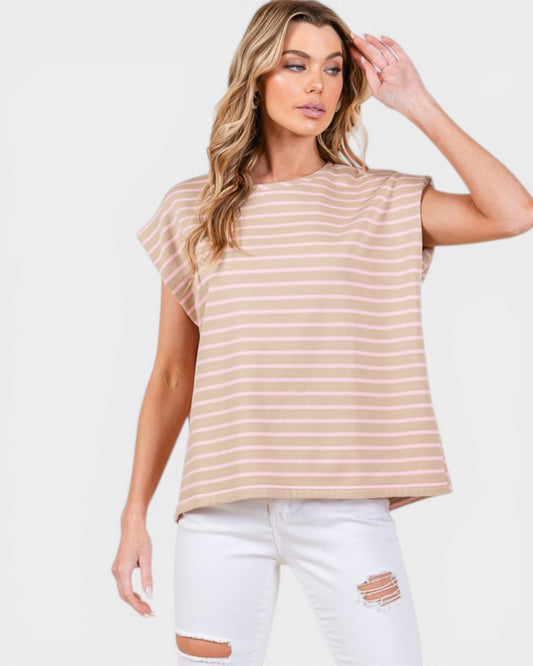 Woman wearing a beige striped sleeveless top and white pants on a white background