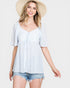 Woman wearing a light blue top and denim shorts with a straw hat on a white background