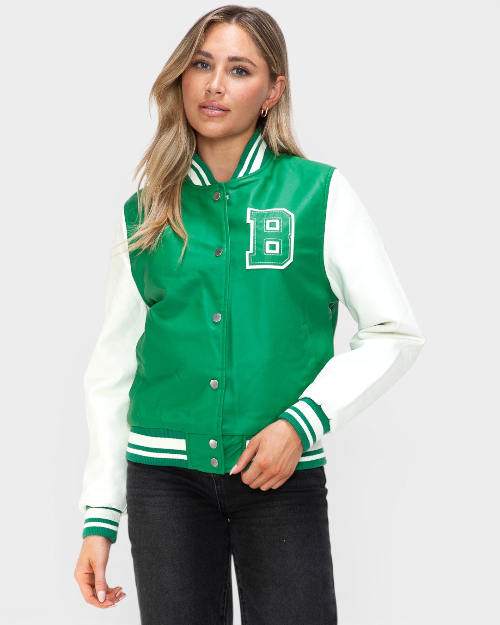 Woman wearing a green and white varsity jacket with a letter 'B' on a light gray background