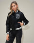 Woman wearing a black varsity jacket with a white letter 'B' on a plain background