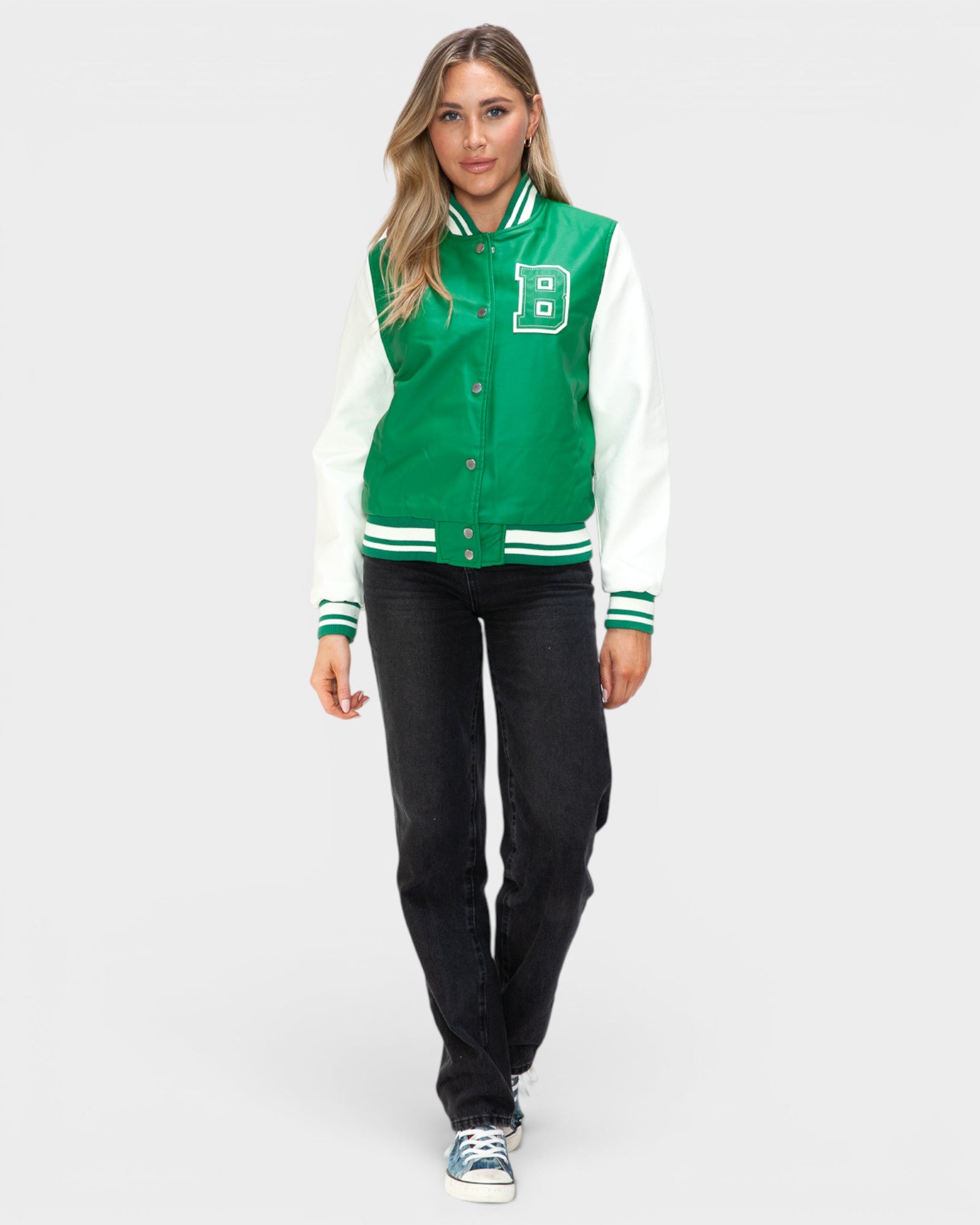 Woman wearing a green and white varsity jacket on a white background