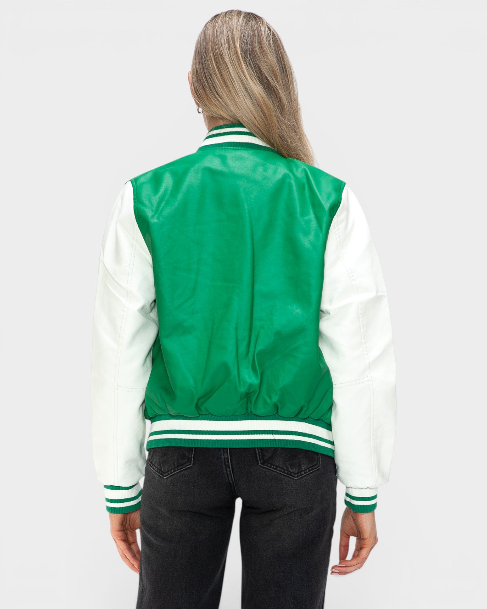 Person wearing a green and white varsity jacket on a plain background