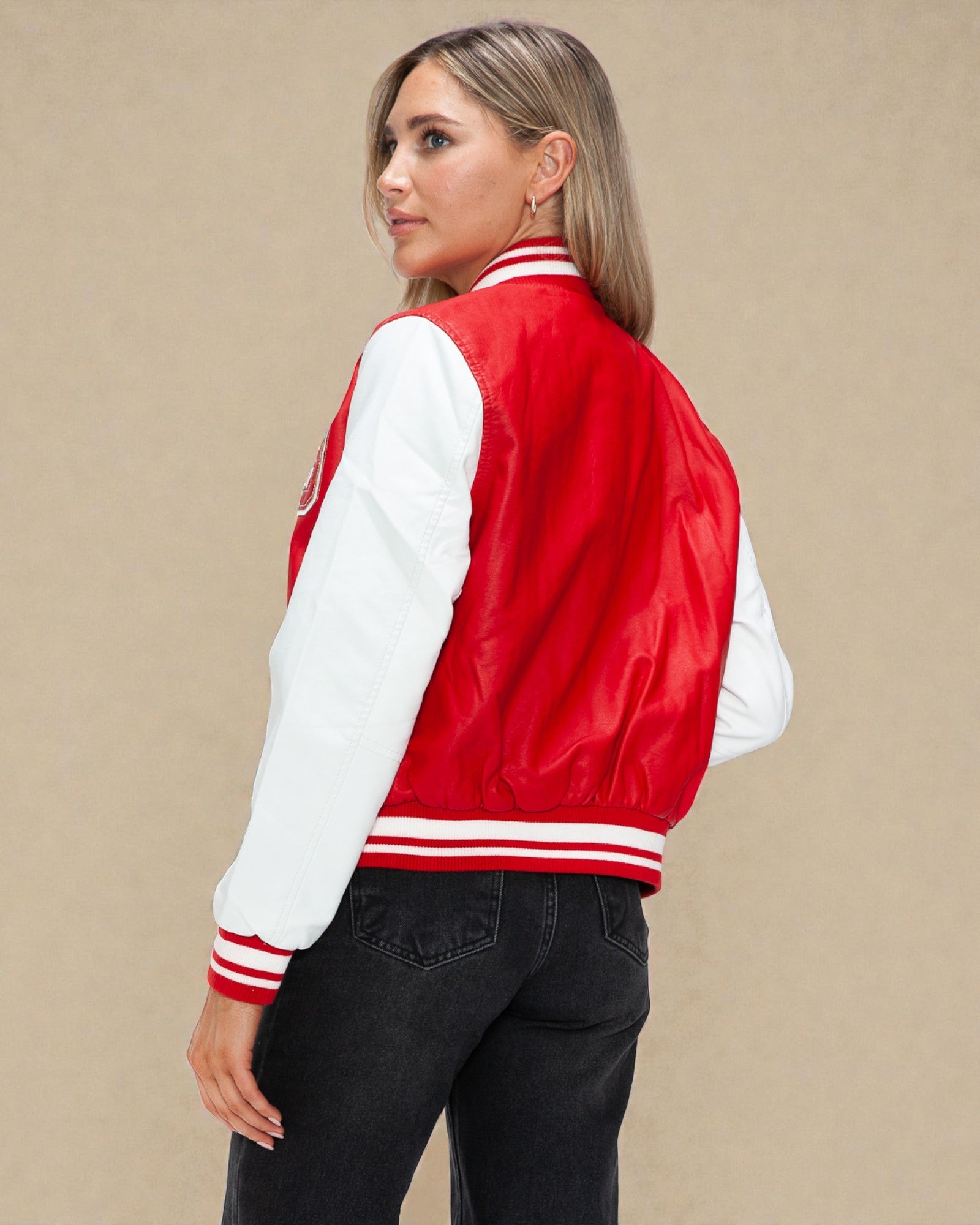 Person wearing a red and white varsity jacket on a beige background