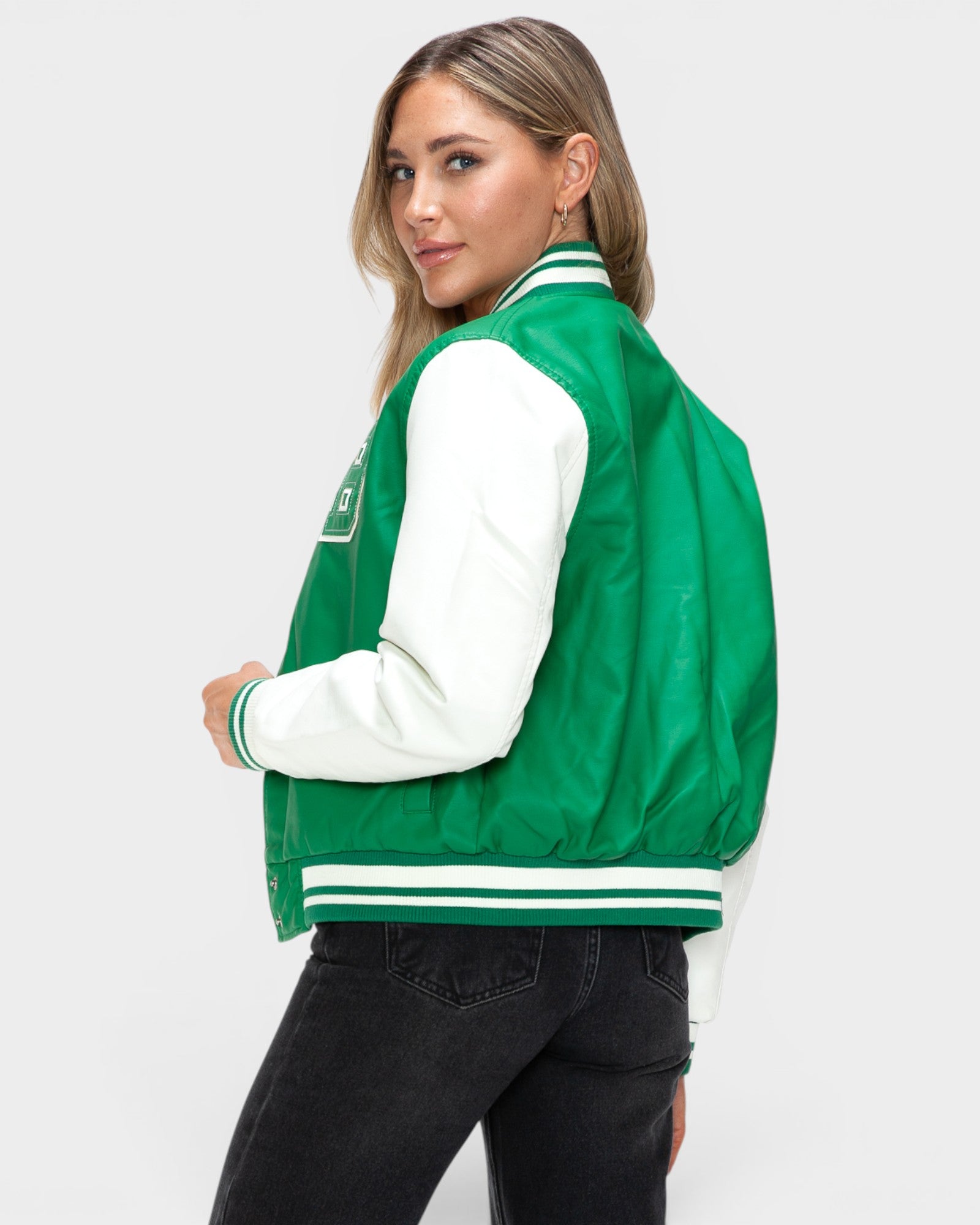Person wearing a green and white varsity jacket on a plain background