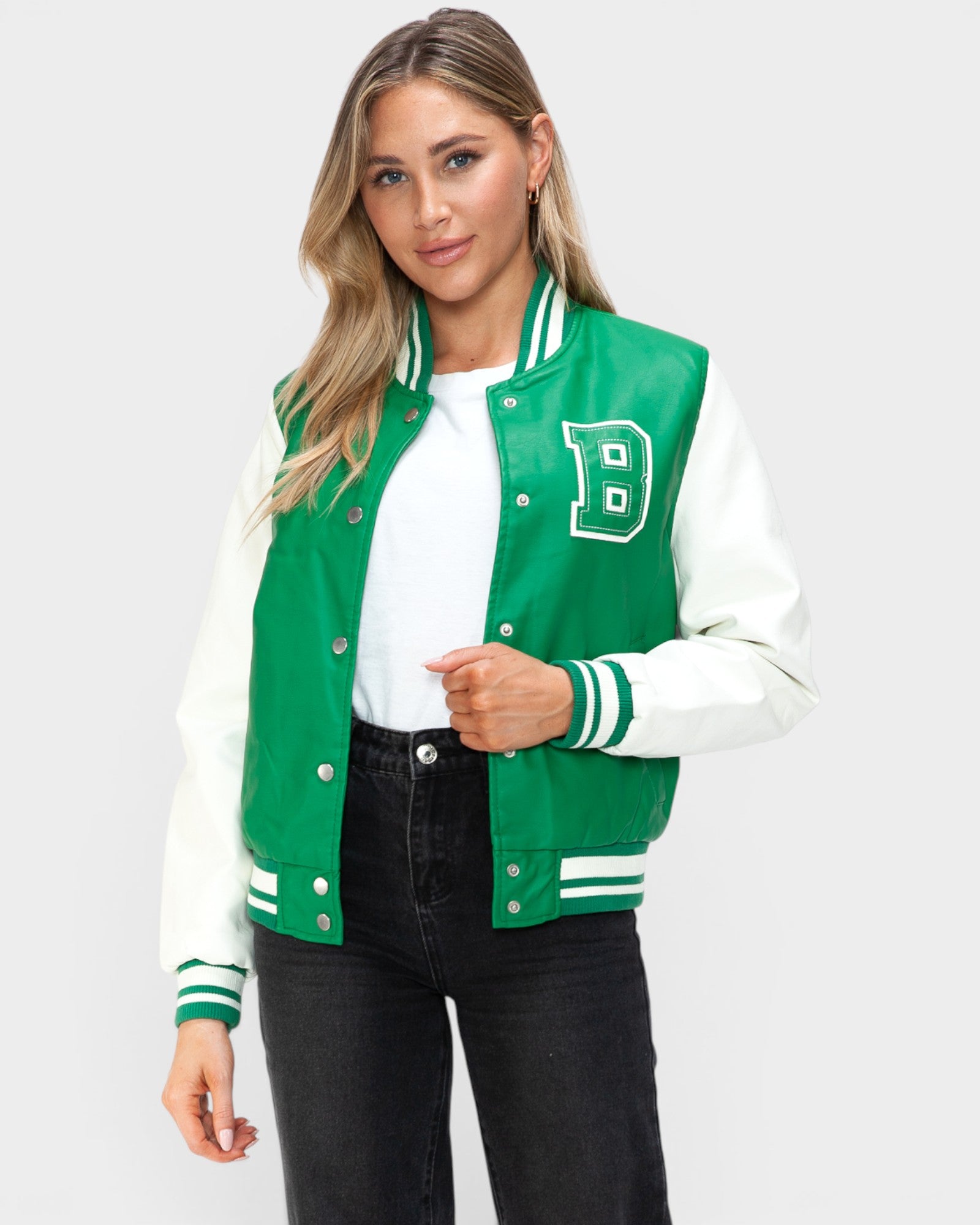 Woman wearing a green and white varsity jacket with a letter 'B' on a plain background