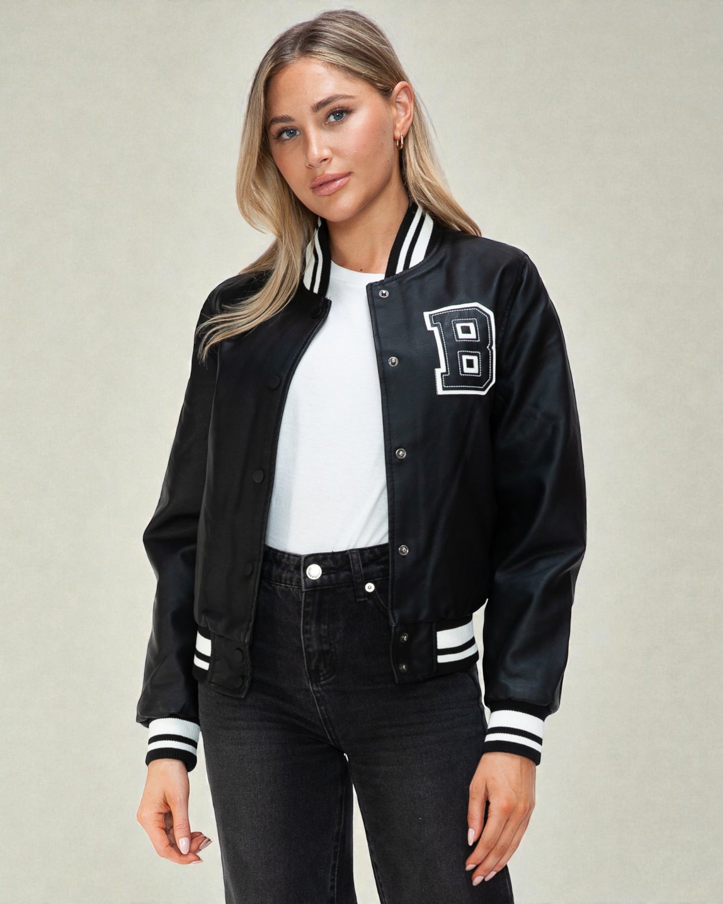 Person wearing a black varsity jacket with a white 'B' logo on a neutral background