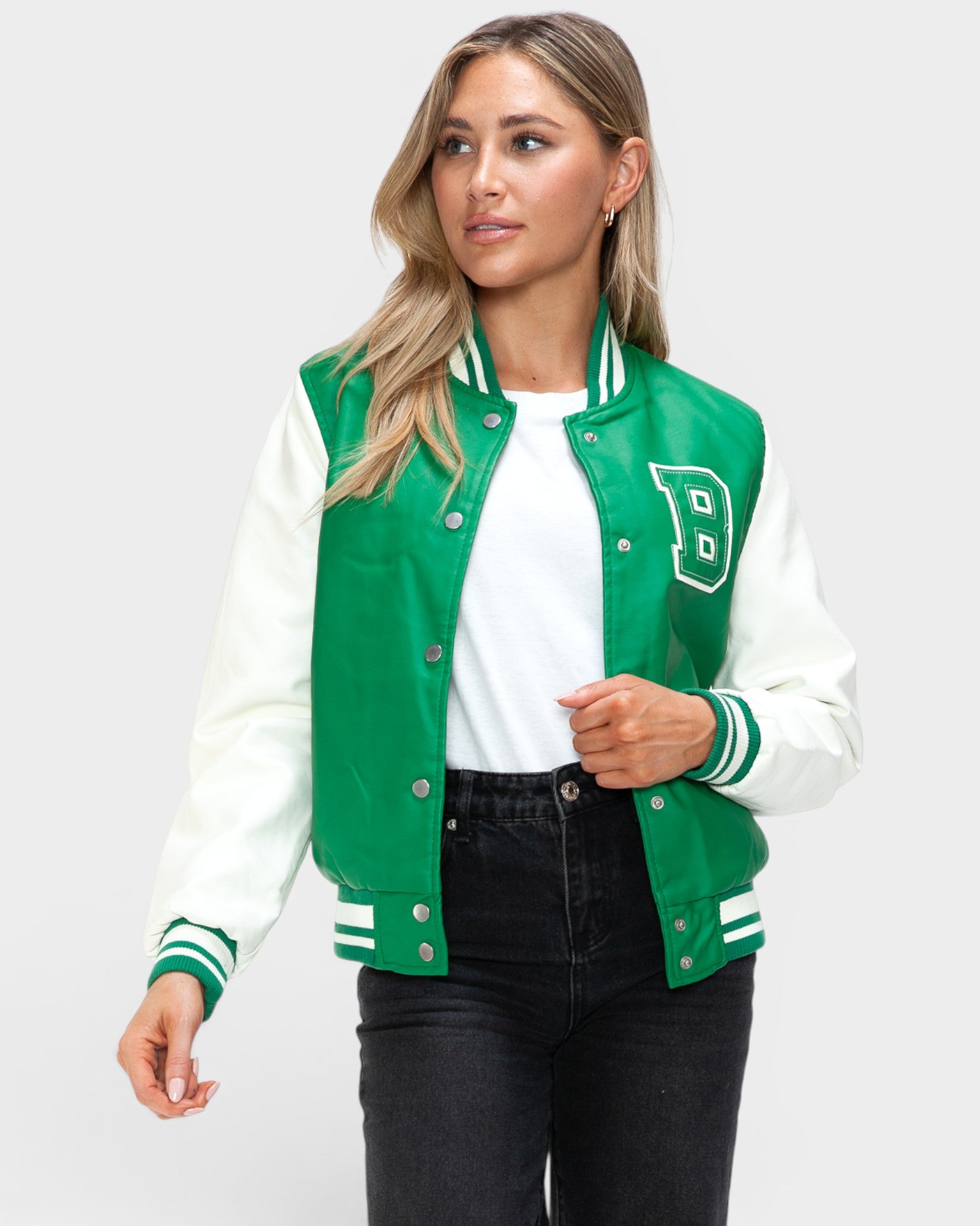 Woman wearing a green and white varsity jacket on a white background