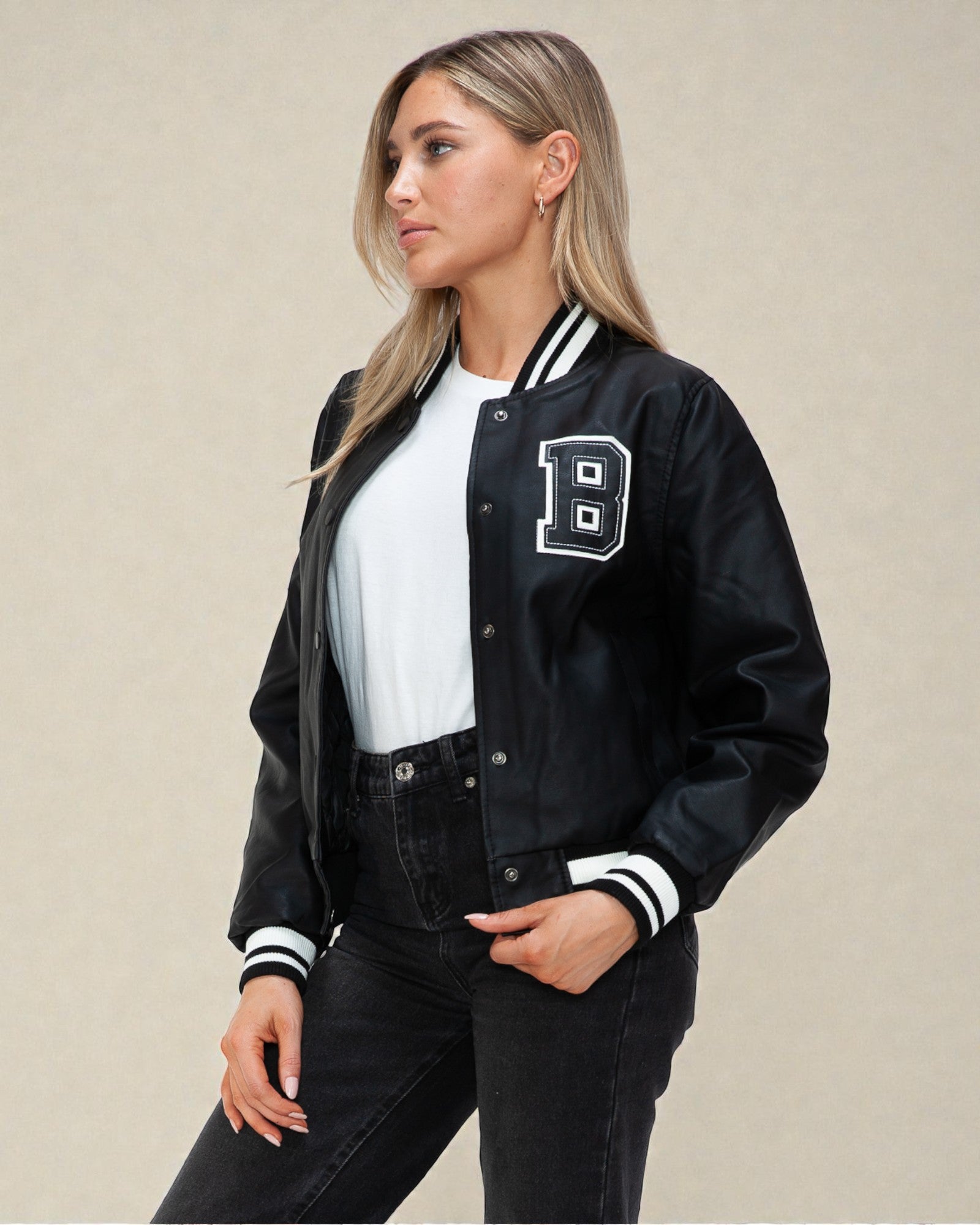 Woman wearing a black varsity jacket with a letter 'B' on a beige background