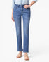 A model wearing a pair of medium-wash blue straight-leg jeans, styled with a light blue shirt and beige strappy sandals, against a plain white studio background.