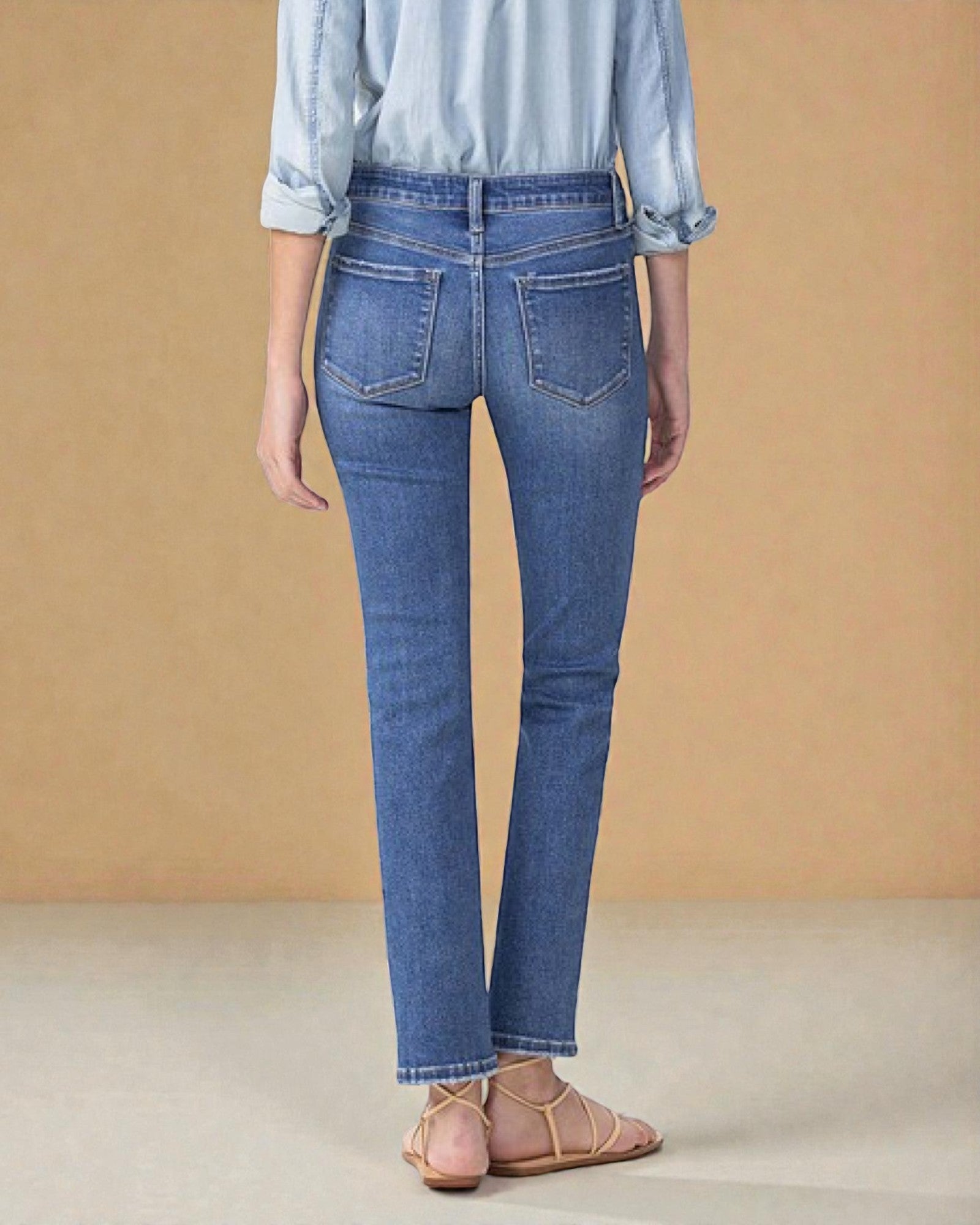 Person wearing blue jeans and a light blue shirt against a beige background